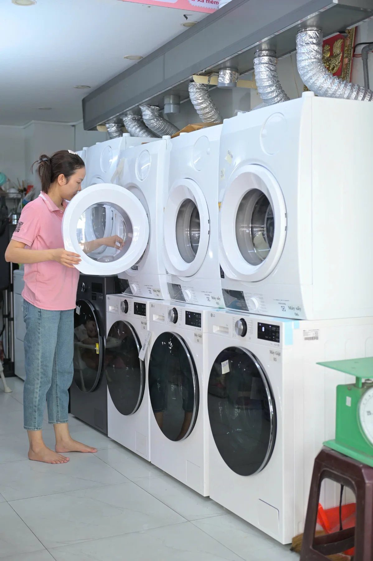 Nhân viên Thanh Ngân mở cửa máy sấy trong dàn máy giặt sấy tại tiệm.